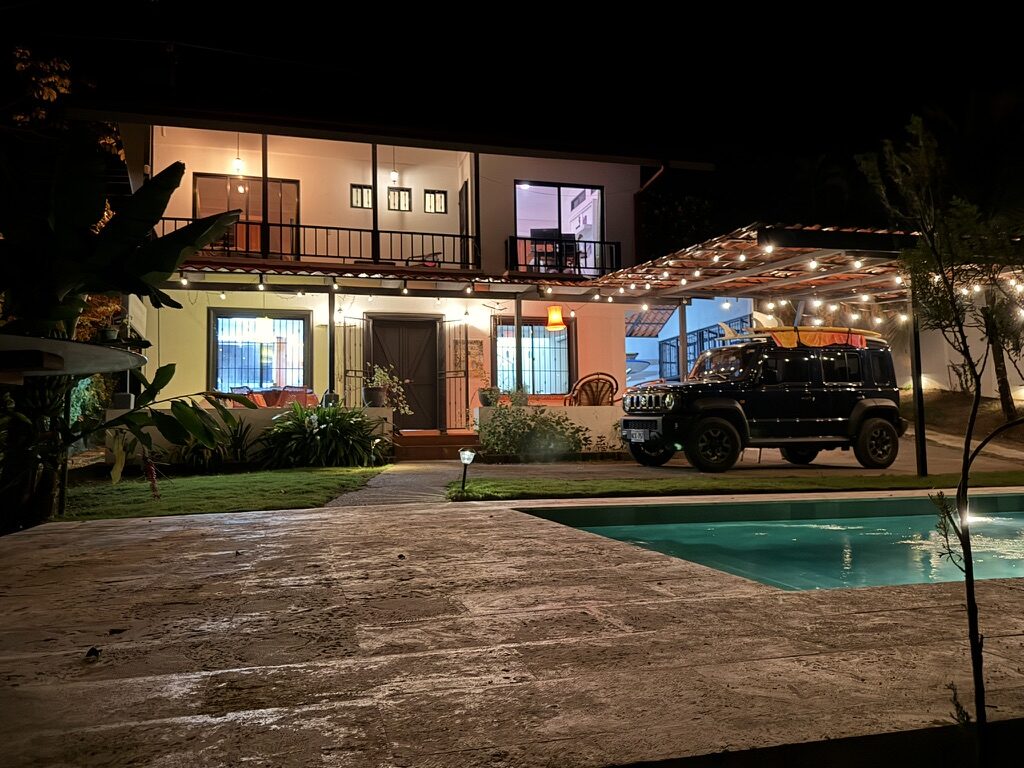 Casa Dame at night, string lights glowing over the carport and the pool in the foreground
